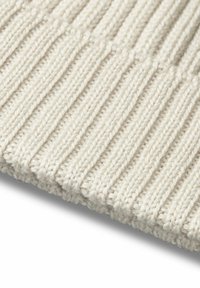 Beige knit fabric features a ribbed texture with distinct, raised lines. The yarn is soft and thick, creating a cozy look.