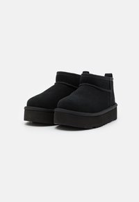 Las botas de tobillo de ante negro presentan una puntera redondeada, costuras mínimas y una suela de goma gruesa para mayor durabilidad y confort.