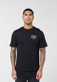 Μαύρο βαμβακερό T-shirt με στρογγυλή λαιμόκοψη και κοντά μανίκια, με λευκό γραφικό κείμενο και αστέρια στο στήθος. Κανονική εφαρμογή, λεία υφή.