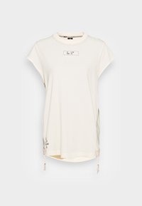 Světle béžové bavlněné tričko s krátkými rukávy, kulatým výstřihem, postranními rozparky a nastavitelnými lemy s dekorativními zdrhovadly a potiskovými akcenty.