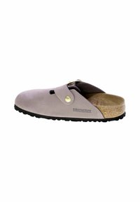 Zoccoli in suede grigio con un sottopiede in sughero beige, suola in gomma nera e una decorative fibbia in metallo. Presenta un'apertura sulla punta per la ventilazione.