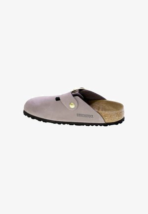 Zoccoli in suede grigio con un sottopiede in sughero beige, suola in gomma nera e una decorative fibbia in metallo. Presenta un'apertura sulla punta per la ventilazione.