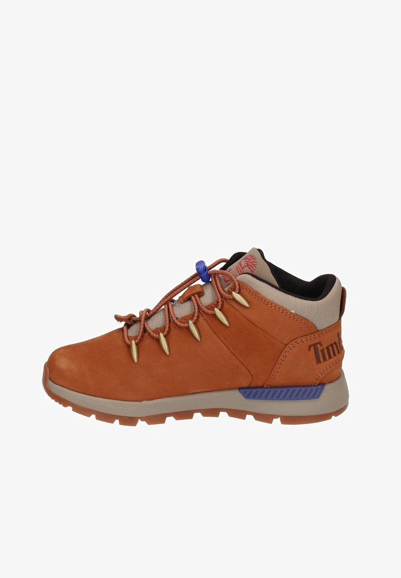 Chaussure de randonnée en daim marron avec des accents texturés, des crochets dorés et un verrou de lacet bleu. Présente un col beige et une semelle en caoutchouc grise.