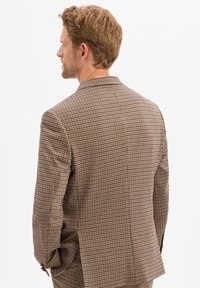Bruine houndstooth-gepatroneerde blazer met een notch lapel, gestructureerde pasvorm en twee zijventilaties. Gemaakt van textuurstof, met subtiele stikseldetails.
