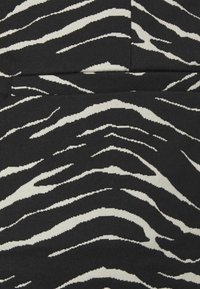 Tessuto nero con un motivo a strisce zebra in bianco, che presenta un design testurizzato con strisce di larghezze diverse.