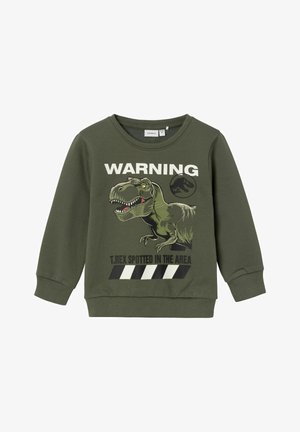 Zelená bavlnená mikina s grafikou dinosaura, textom "UPOZORNENIE" a čierno-bielymi pruhmi. Obsahuje rebrované manžety a výstrih.