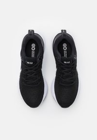 Zapatillas deportivas negras con parte superior de punto texturizado, cierre de cordones y entresuela de espuma blanca. Presenta detalles del logo en la lengüeta y los laterales.
