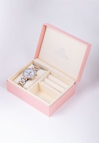 Orologio da polso argento e rosegold con quadrante bianco, racchiuso in una scatola di gioielli rosa con imbottitura color crema e tre scomparti interni.