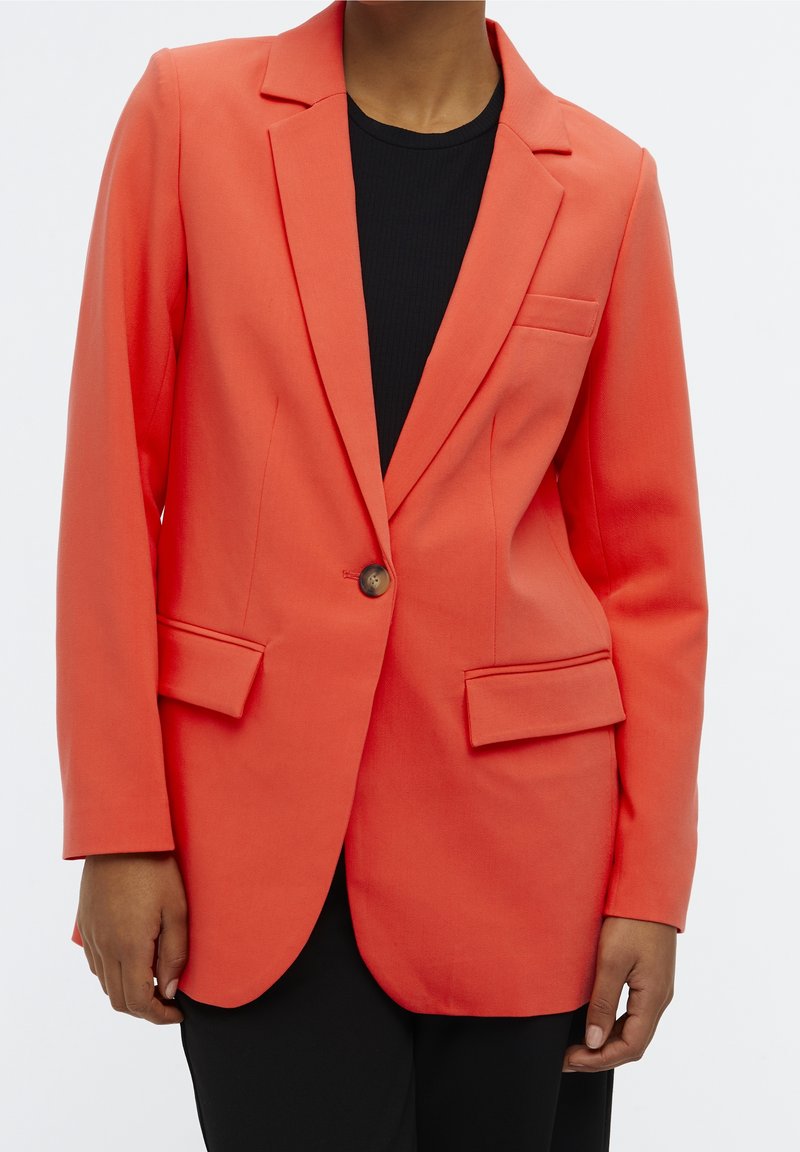 Blazer de coral con un diseño ajustado, cierre de un botón, dos bolsillos frontales y solapa tipo notch. Fabricado con un tejido suave de acabado mate.