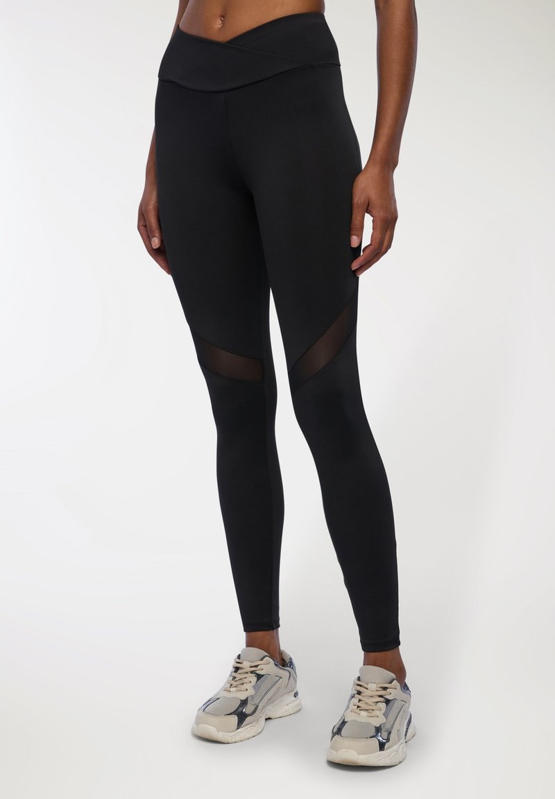 Czarne legginsy sportowe z wysokim stanem, z akcentami w postaci paneli z siateczki na dolnej części nóg. Gładka tekstura i dopasowany krój.