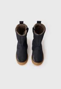 Marineblauwe leren enkelboots met een zachte bruine nepbontvoering en lichtbruine rubberen zolen, voorzien van een zijrits en hulpmiddel om aan te trekken.