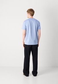 T-shirt en coton bleu clair à manches courtes, col rond et coupe décontractée, associé à un pantalon noir à jambes larges.