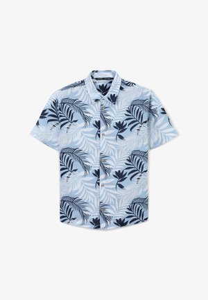 Camicia a maniche corte con bottoni di colore azzurro chiaro con motivo di foglie tropicali blu scuro, abbinata a pantaloni corti blu navy e sneakers alte bianche.