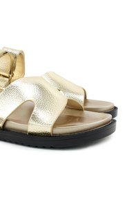 Gouden metallic sandalen met een gestructureerde afwerking, open teenontwerp, twee brede banden en een lichte zwarte zool. Glad, gewatteerd voetbed.