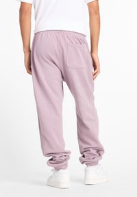 Hellviolette Jogginghosen aus einem Baumwollmischgewebe mit entspanntem Schnitt, elastischem Bund und Bündchen am Saum. Mit einer einzelnen Gesäßtasche.