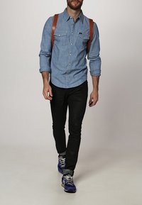 Vaaleansininen chambray-paitapusero, mustat slim fit -housut ja violetit urheilukengät. Ruskeat nahkaiset olkahihnat.