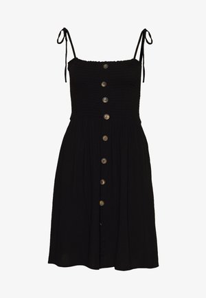 Vestido negro sin mangas con corpiño fruncido, tirantes ajustables con lazo en los hombros y una fila frontal de botones marrones desde arriba hasta el bajo.