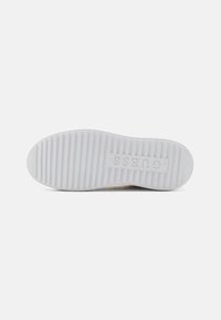 Semelle de chaussure de sport en caoutchouc blanc avec des rainures horizontales pour la traction, arborant un logo moulé avec un texte en relief. Texture lisse, forme arrondie.