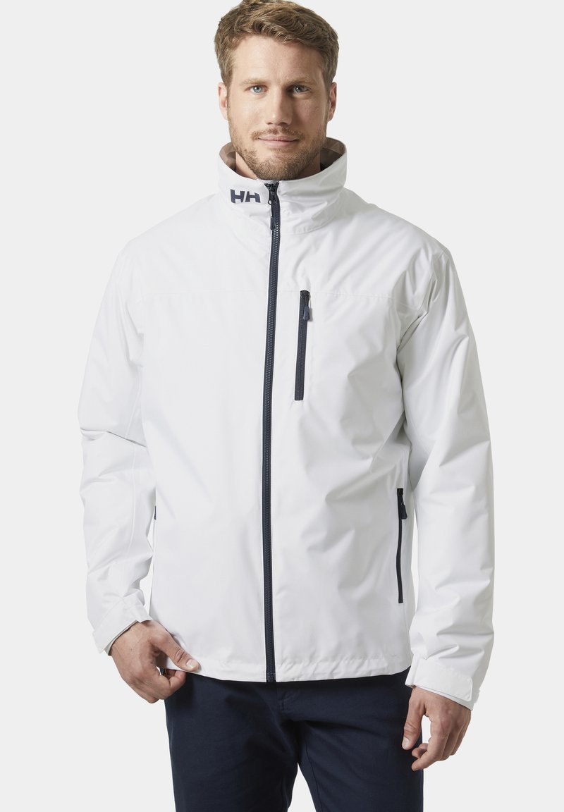 Chaqueta impermeable blanca con un alto collar, cremallera frontal y detalles en azul marino. Incluye bolsillos con cremallera y detalles de herrajes en contraste.