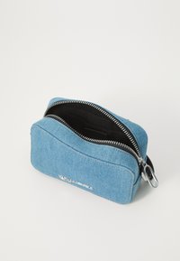 Blue denim zippered pouch with black lining, padded structure, silver zipper accent, and embossed logo on the front, compact rectangular design.