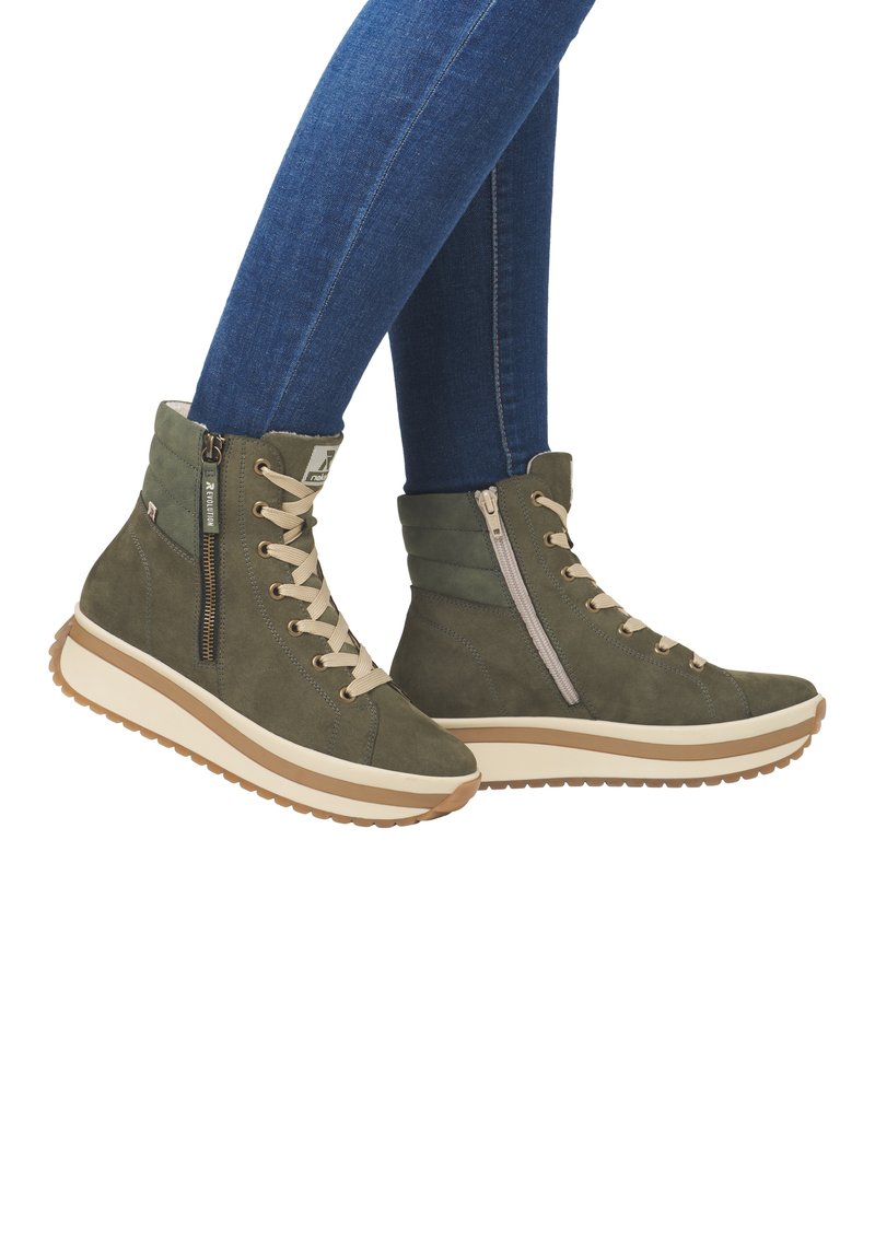 Bottines en daim vertes avec lacets beiges et zip sur le côté, dotées d'une épaisse semelle couleur crème et d'un fond en caoutchouc texturé.