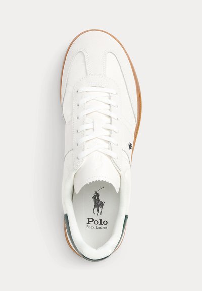 Biela teniska Polo Ralph Lauren s bielymi šnúrkami, gumovou podrážkou a čiernym logom hráča póla na vnútornej podrážke a na vonkajšej strane.