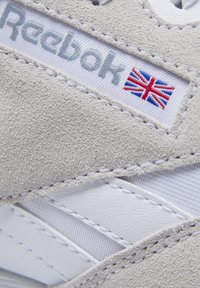 Weiß-graue Reebok-Sneaker aus Wildleder und Leder mit gesticktem britischen Flaggenemblem und strukturierten Akzenten.