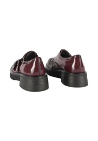 Scarpe in pelle vernice bordeaux con punta arrotondata e tacco basso in black. Presentano dettagli brogue decorativi lungo i bordi.