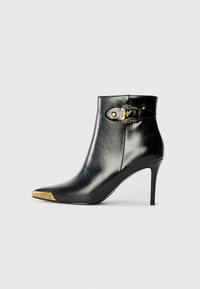 Sorte skinn ankelstøvler med spiss tå og stiletthæl. Har en gullakk accent på tåpartiet og en detaljer med spenne på siden.