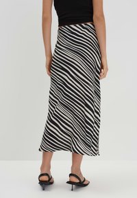 Gonna midi a strisce nera e crema con un design fluido, realizzata in tessuto morbido. Presenta una vita alta e una leggera brillantezza.