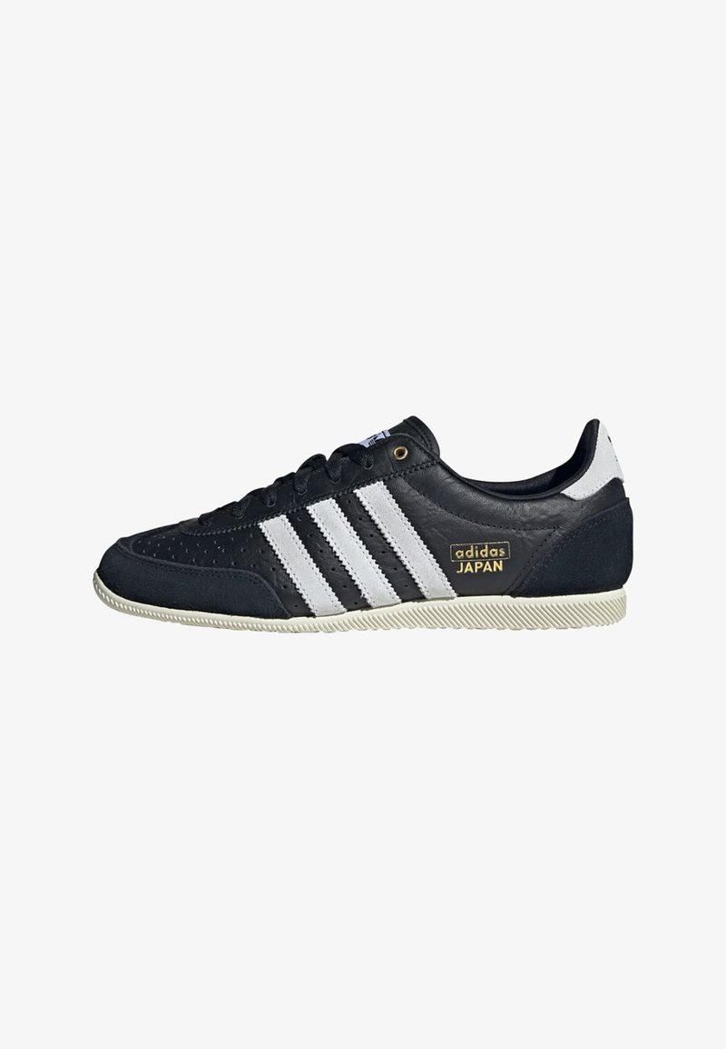 Sorte lær sneakers med tre hvite striper, teksturert overflate, gull "adidas JAPAN" logo, og gummisåle med gripe mønster.