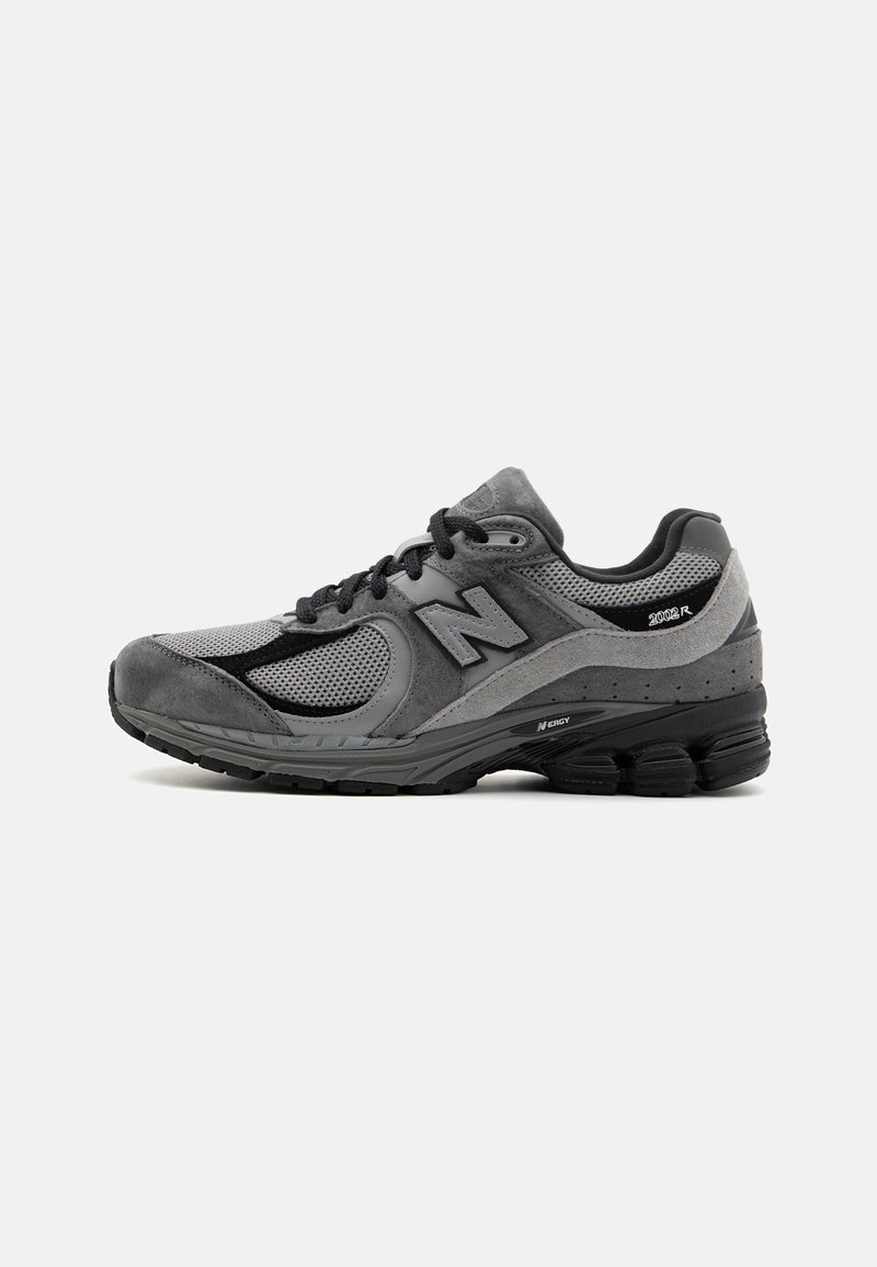 Baskets de sport grises, combinant mesh et daim, avec une semelle noire et des accents réfléchissants. Conçues pour le confort et la stabilité lors des mouvements.