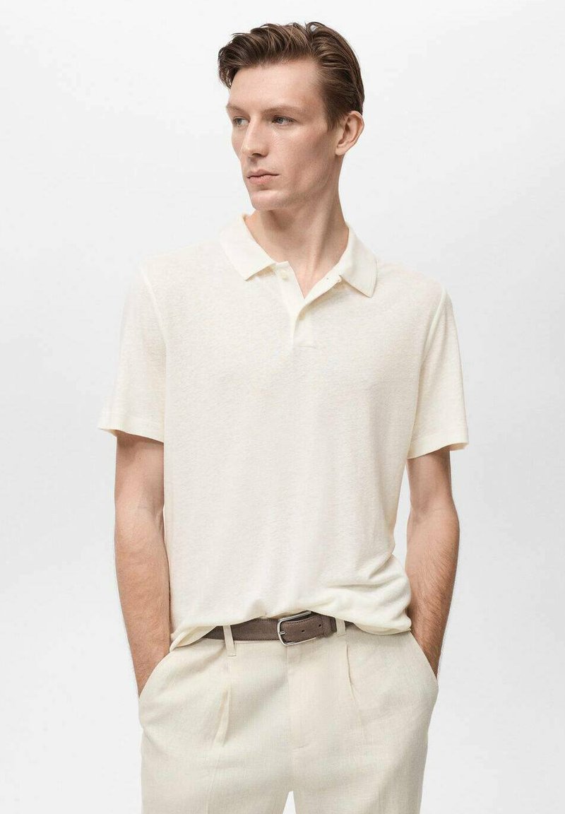 Polo a maniche corte di colore crema chiaro, realizzato in tessuto morbido con una leggera finitura strutturata. Presenta un colletto classico e una vestibilità rilassata.