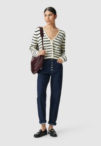 Cardigan a righe in maglia con bottoni, jeans scuri a vita alta, e mocassini neri. Borsa a tracolla bordeaux con manico.