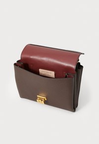 Brown textured leather bag with a burgundy flap, gold hardware clasp, and a label inside. Rectangular shape with smooth edges.
