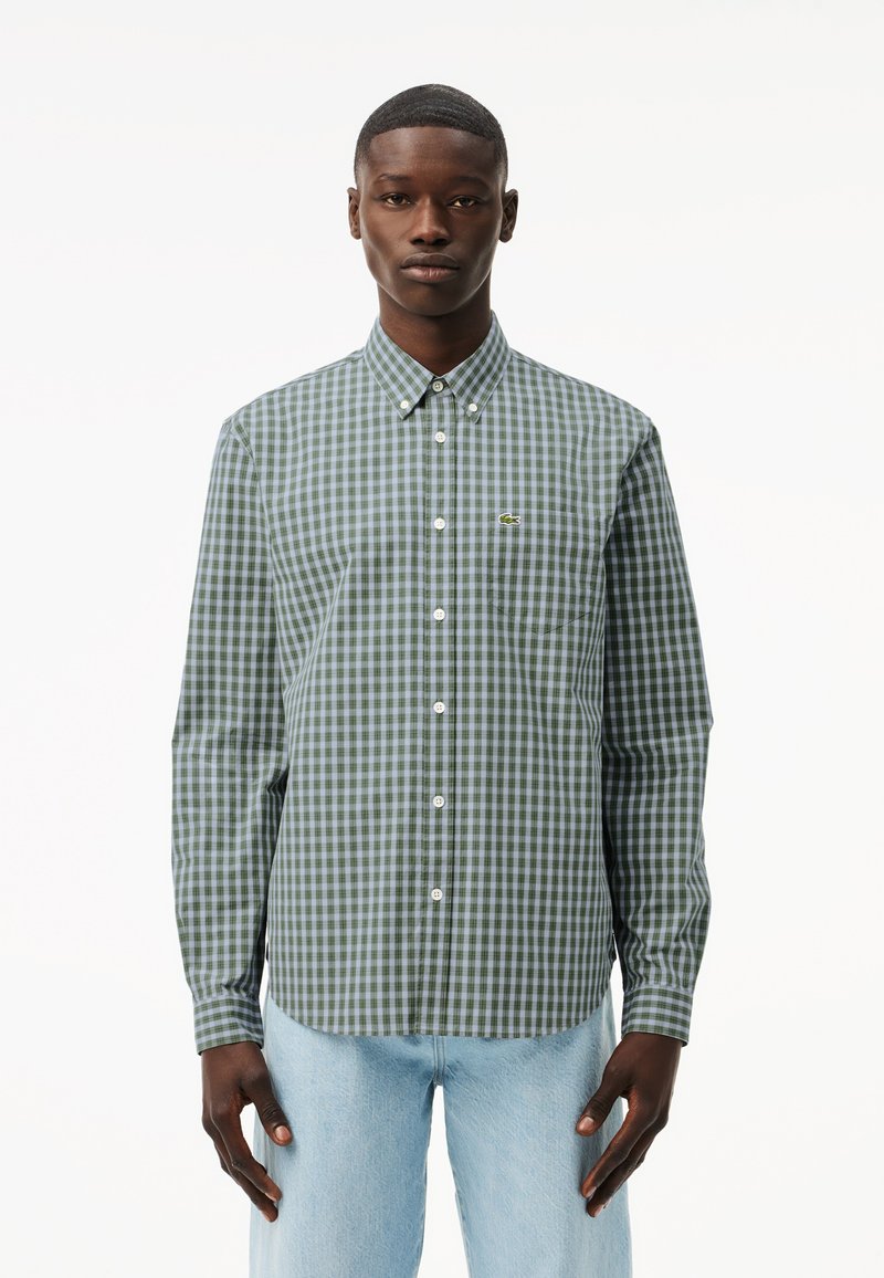 Camisa de cuadros en verde y azul marino, con botones, de mangas largas y cuello, que presenta un pequeño logo en el pecho y botones blancos.