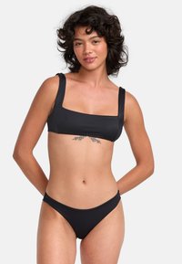 Black bikini set featuring a square-neck top with wide straps and minimal coverage bottoms, crafted from smooth, stretchy material.