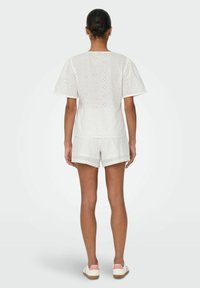 Hvid øjet stof top med korte ærmer, parret med matchende shorts. Enkel design med et struktureret mønster og en afslappet pasform.
