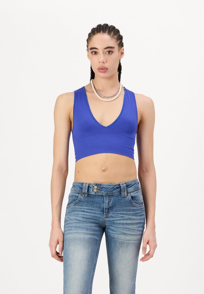 Blå ribbet crop top med V-hals, paret med lyse denimjeans med en falmet design og klassisk lukking med tre knapper.