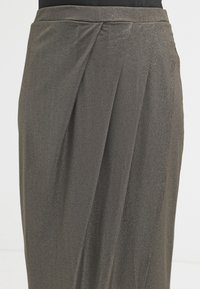 Lång mörkgrå kjol i glittrigt material med en jämn textur, som har draperade detaljer och en subtil lyster.