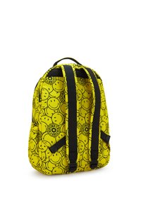 Sac à dos jaune avec des bretelles noires réglables et un motif de visages souriants contours noirs et de logos circulaires.