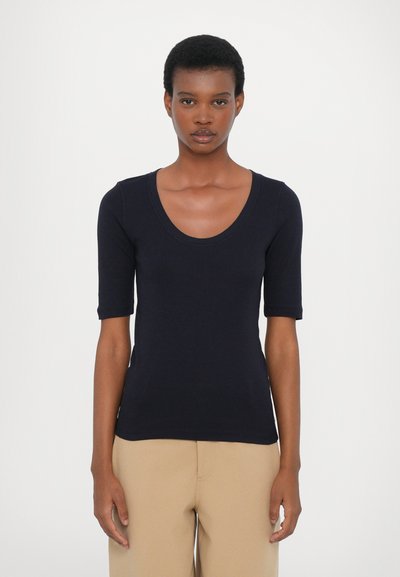 Haut à manches courtes bleu marine avec un col en U. Fabriqué en tissu lisse, il présente une coupe ajustée et des détails de couture subtils.