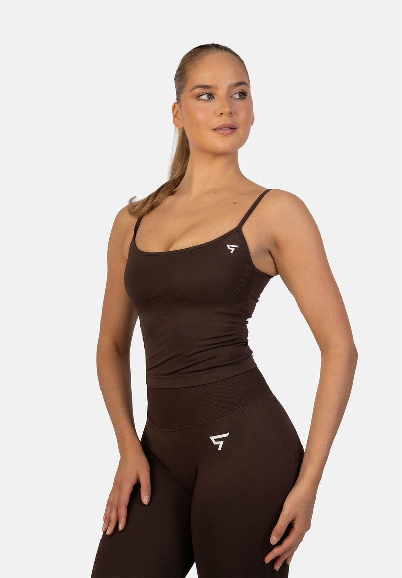 Top corto deportivo marrón y leggings de cintura alta, con tirantes finos ajustables y un acento del logo blanco en la cinturilla. Textura suave.