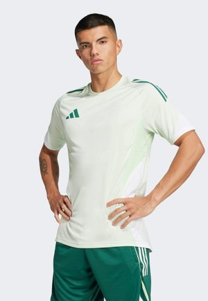 Maglietta sportiva verde chiaro con strisce verdi sulle spalle e pannello laterale bianco. Presenta il logo Adidas e maniche corte, abbinata a pantaloni corti verdi.