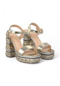 Sandali platform dorati con un design a fascia ampia, tacchi a blocco decorati con perline e texture intrecciata, e chiusura a fibbia.