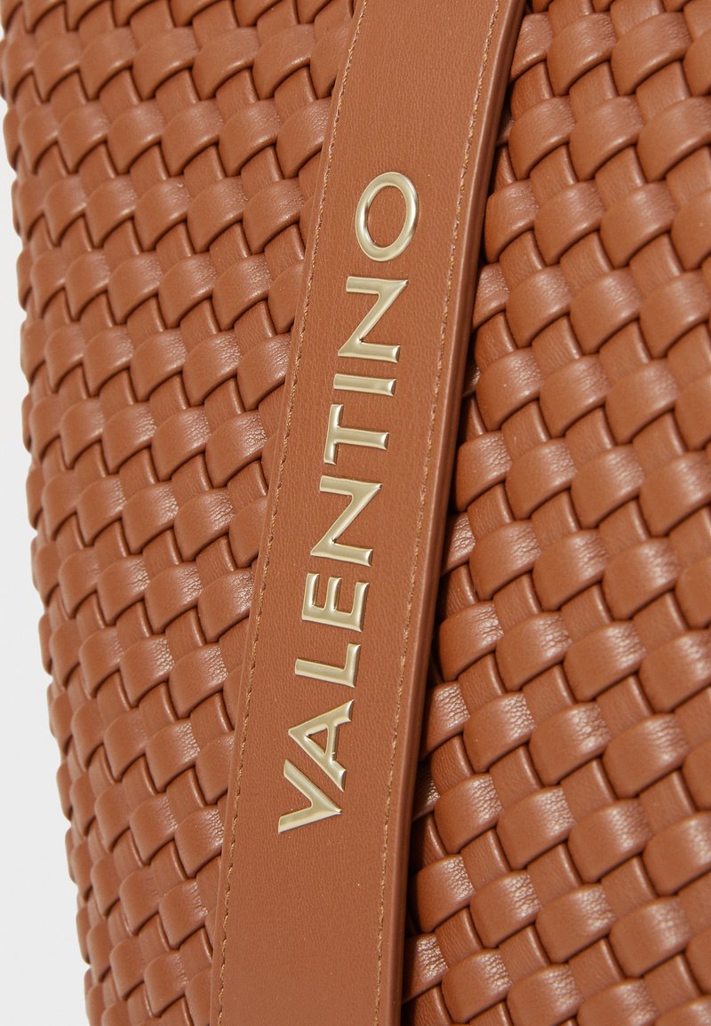 Braune geflochtene Ledertasche mit glatter Textur, die ein auffälliges goldenes "VALENTINO"-Logo an einem Riemen aufweist.