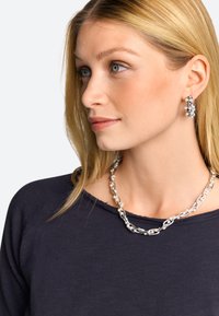 Collana in argento con anelli alternati lisci e Texturizzati, abbinata a grandi orecchini a cerchio in argento con piccole orbite bianche.