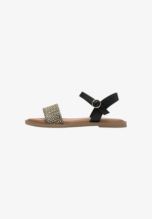 Sandali neri e marroni con una fascia intrecciata a motivo e una cinghia alla caviglia regolabile con fibbia circolare. Sole piatto con cuciture decorative.