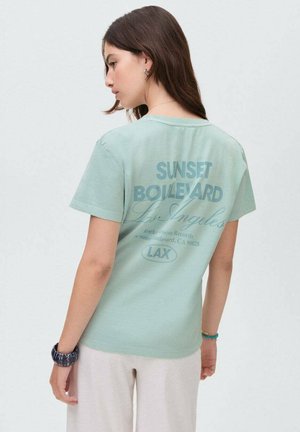 T-shirt turquoise à manches courtes avec un design graphique comportant le texte "SUNSET BOULEVARD" et "Los Angeles" au dos. Matière douce.