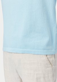 Ljusblå bomullst-shirt med rund halsringning och korta ärmar, kombinerad med ljusbeige linnebyxor med sidofickor.